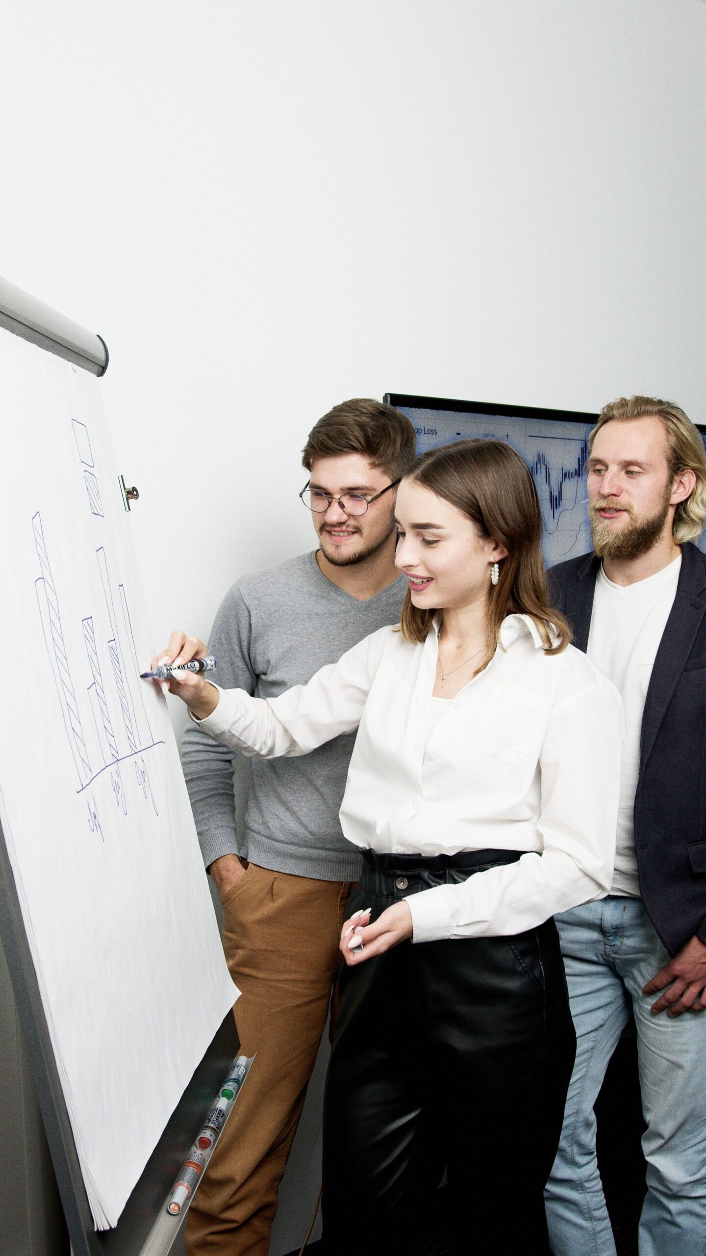 Drei Menschen im Business-Look erarbeiten an einem Whiteboard einen Graphen.